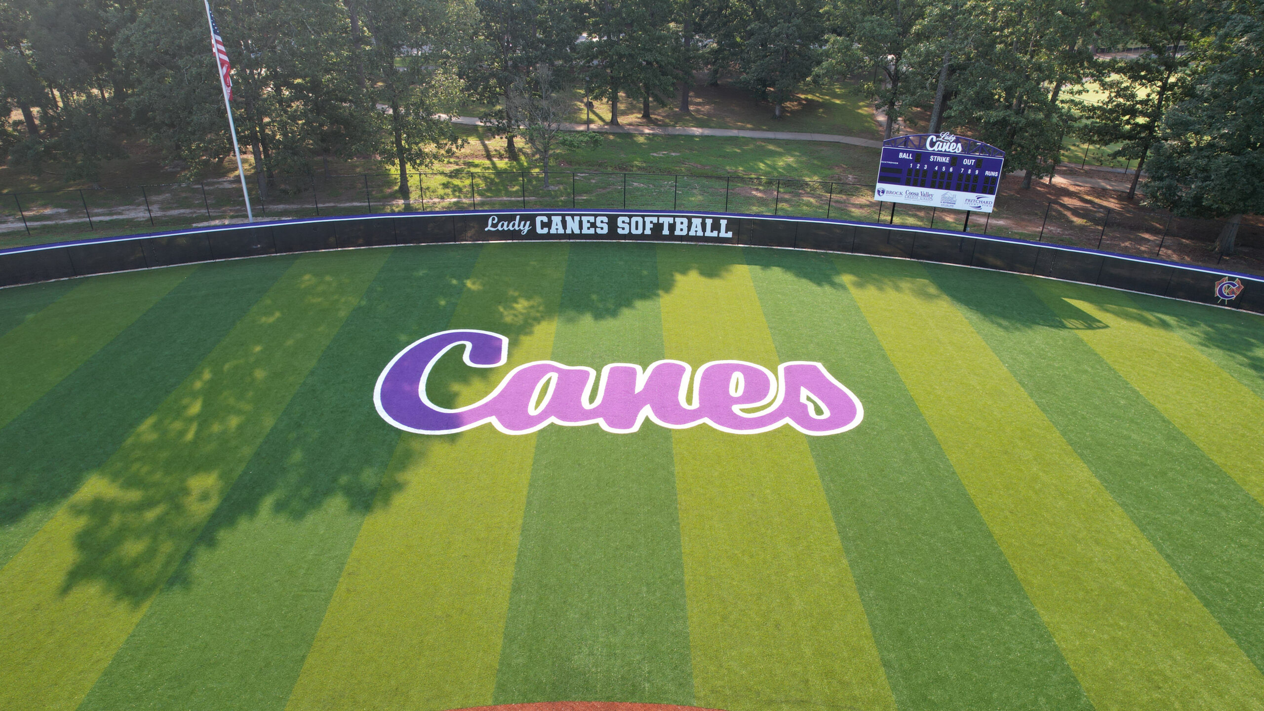 Clean, low-altitude aerial featuring the purp Lady Canes wordmark and striped outfield pattern